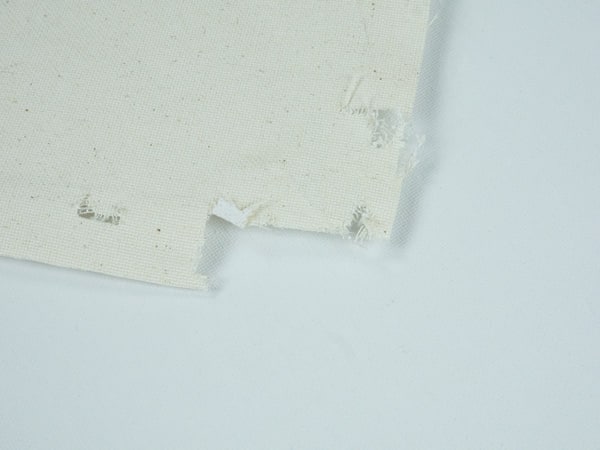 A comparison between the treated and untreated sides of canvas- the untreated has a bit more color and texture than the treated.