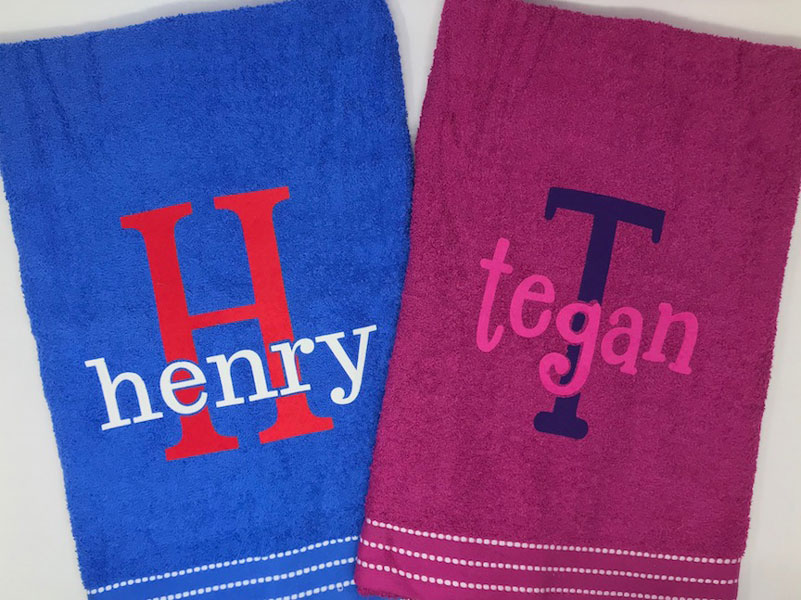Two finished monogrammed towels- one reading "Henry" and one reading "Tegan"
