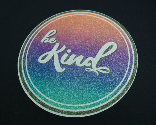 The sublimated "Be Kind" design pressed onto GlitterFlex Ultra and also pressed onto a black shirt